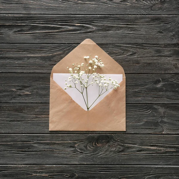 Envelope with card and flowers on dark wooden background