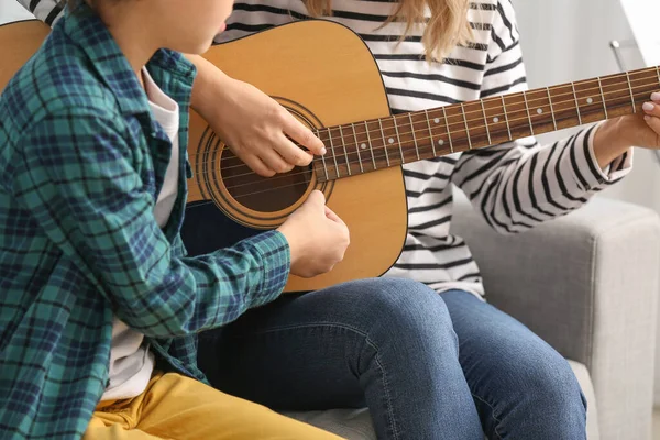 Private music teacher giving guitar lessons to little boy at home