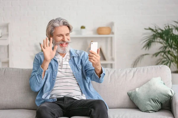 Happy elderly man with mobile phone at home