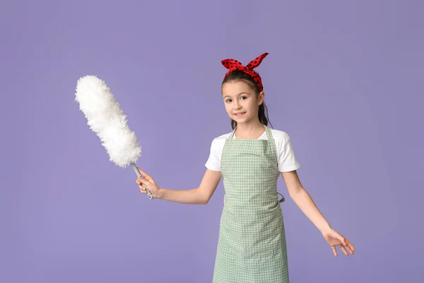 Little housewife with dust brush on color background