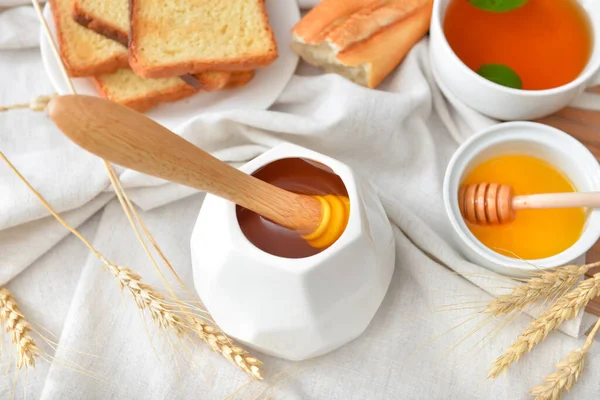 Tasty honey with bread and tea on table