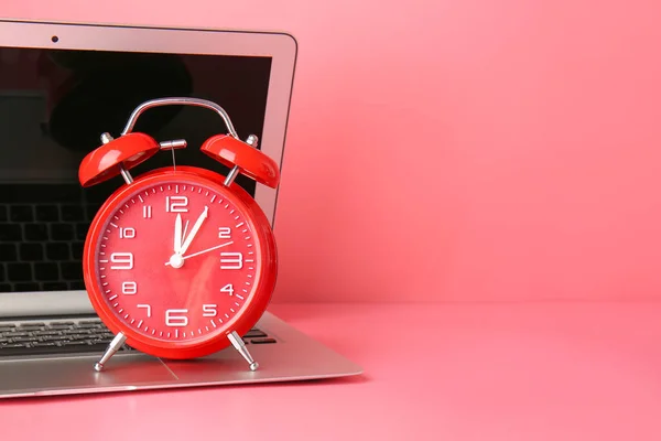 Alarm clock and laptop on color background. Time management concept
