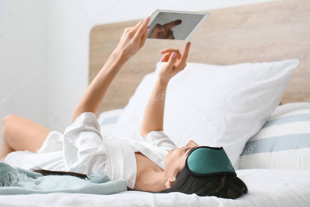 Morning of beautiful young woman with tablet computer in bedroom