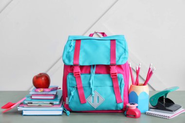 Okul çantası ve kırtasiye malzemesi ahşap masada.