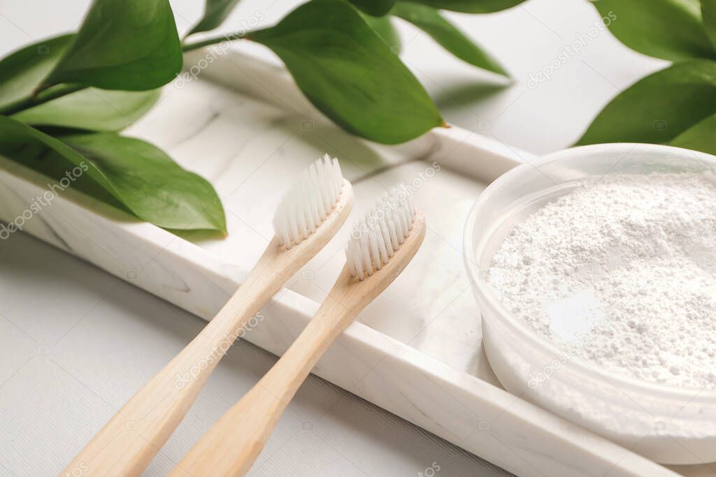 Wooden tooth brushes with toothpaste powder on light background