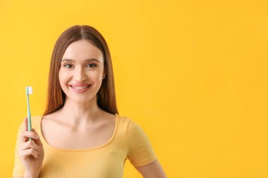 Güzel gülüşü ve arka planda diş fırçası olan genç bir kadın.