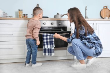 Anne ve oğlu mutfakta birlikte yemek pişiriyor.