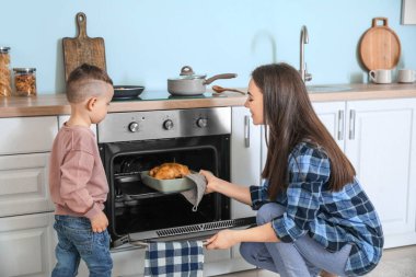 Anne ve oğlu mutfakta birlikte yemek pişiriyor.