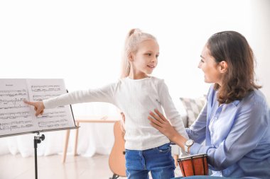 Özel müzik öğretmeni evde küçük bir kıza ders veriyor.