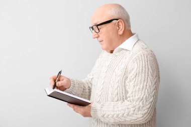 Aydınlık arkaplanda defteri olan yaşlı bir adamın portresi