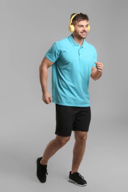 Gri arka planda sportif koşan genç adam
