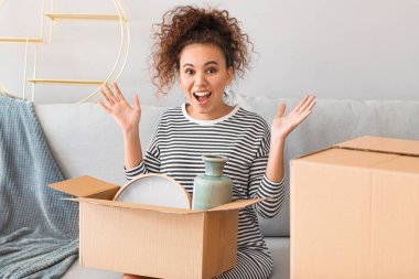 Yeni evinde taşınma kutusuyla mutlu genç bir kadın.