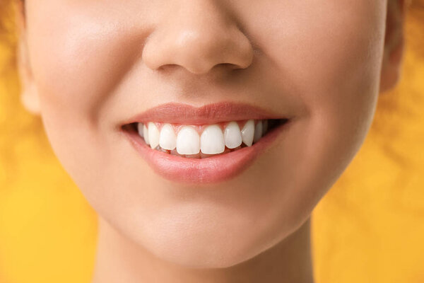 Happy woman with healthy teeth on color background, closeup