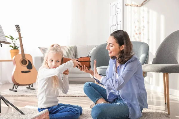 Private music teacher giving lessons to little girl at home