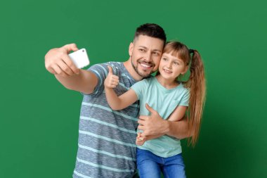Babası ve küçük kızı renk geçmişinde selfie çekiyorlar.