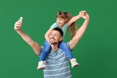 Babası ve küçük kızı renk geçmişinde selfie çekiyorlar.