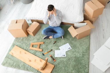 Stresli adam evde mobilya montajı yapıyor.