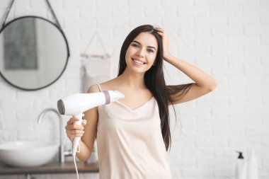 Banyoda saç kurutma makinesi olan güzel bir kadın.