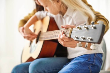Özel müzik öğretmeni evdeki küçük kıza gitar dersi veriyor, yakın çekim.
