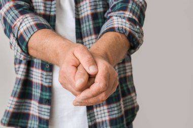 Gri arka planda Parkinson sendromu olan yaşlı adam, yakın plan.