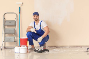 Erkek ressam odada tamirat yapıyor.