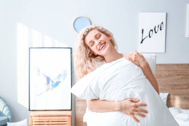 Morning of happy young woman with pillow in bedroom