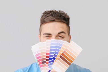 Gri arkaplanda renk örnekleri olan genç bir adam.