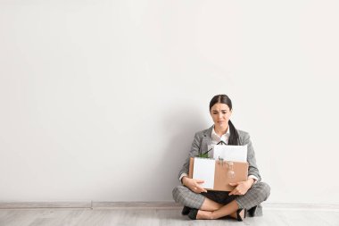 Üzgün kovulmuş kadın ışık duvarının yanında oturuyor.