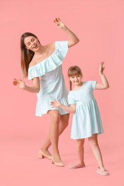 Mutlu anne ve küçük kızı renkli arka planda dans ediyorlar