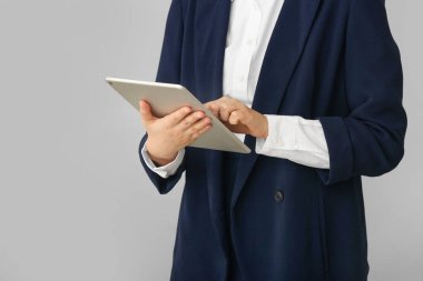 Gri arka planda tablet bilgisayarı olan iş kadını