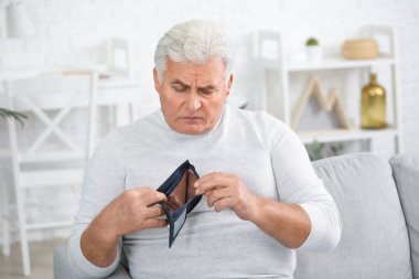 Evde çantası olan üzgün yaşlı bir adam.