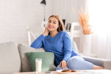 Evde kalın kazaklı güzel bir kadın var.