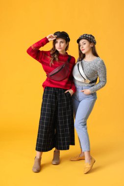 Renkli arka planda kalın kazaklı genç kadınlar