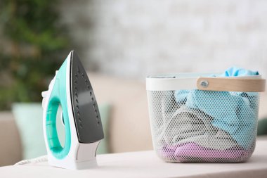 Elektrikli ütü ve giysiler evde sepette.