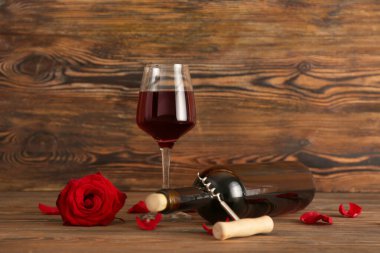 Bir şişe şarap, cam ve güller masada.