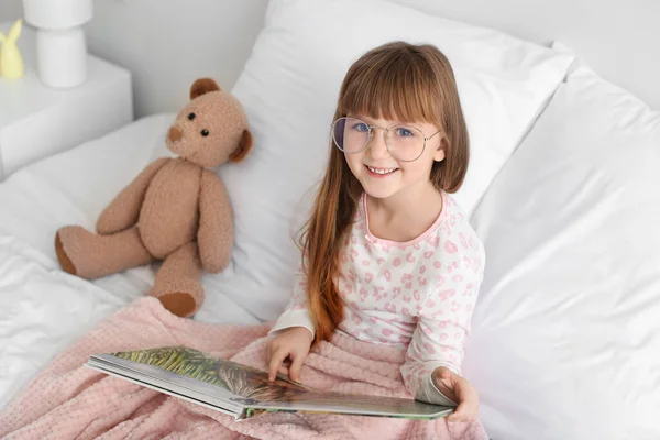 Yatakta Kitap Okurken Gözlük Takan Tatlı Küçük Kız — Stok fotoğraf