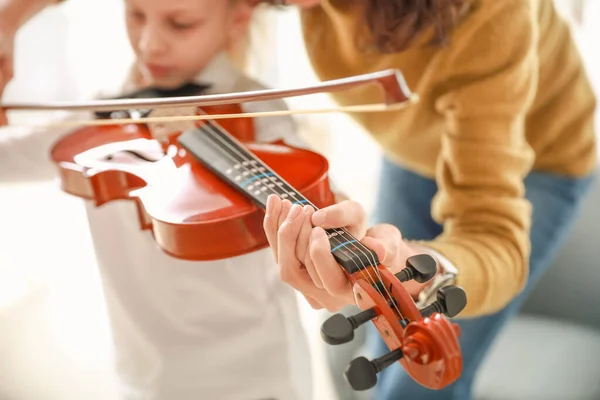 Private music teacher giving violin lessons to little girl at home