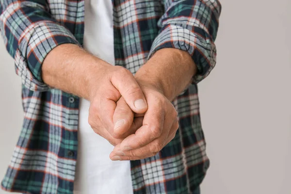 Gri arka planda Parkinson sendromu olan yaşlı adam, yakın plan.