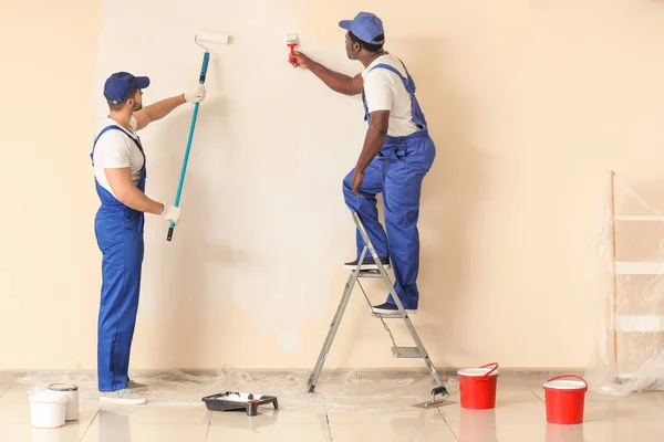 Male painters doing repair in room