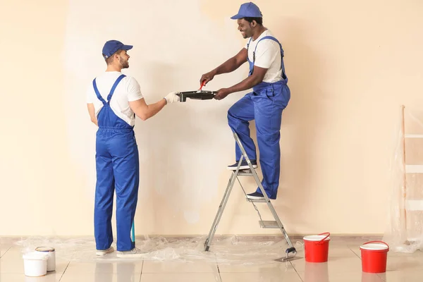 Male painters doing repair in room