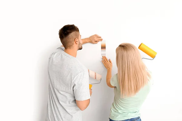 Genç Çift Beyaz Arkaplanda Duvar Rengini Seçiyor — Stok fotoğraf