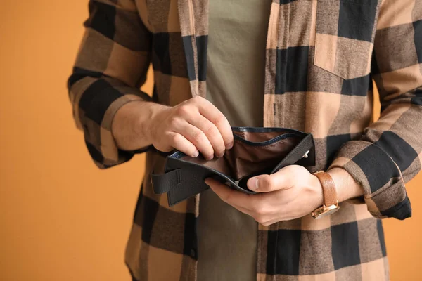 Man with empty purse on color background, closeup