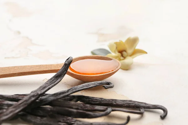 Spoon with aromatic vanilla extract on table