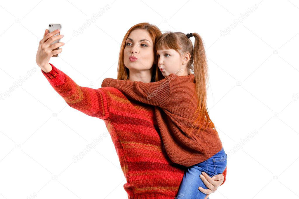 Mother and her little daughter taking selfie on white background