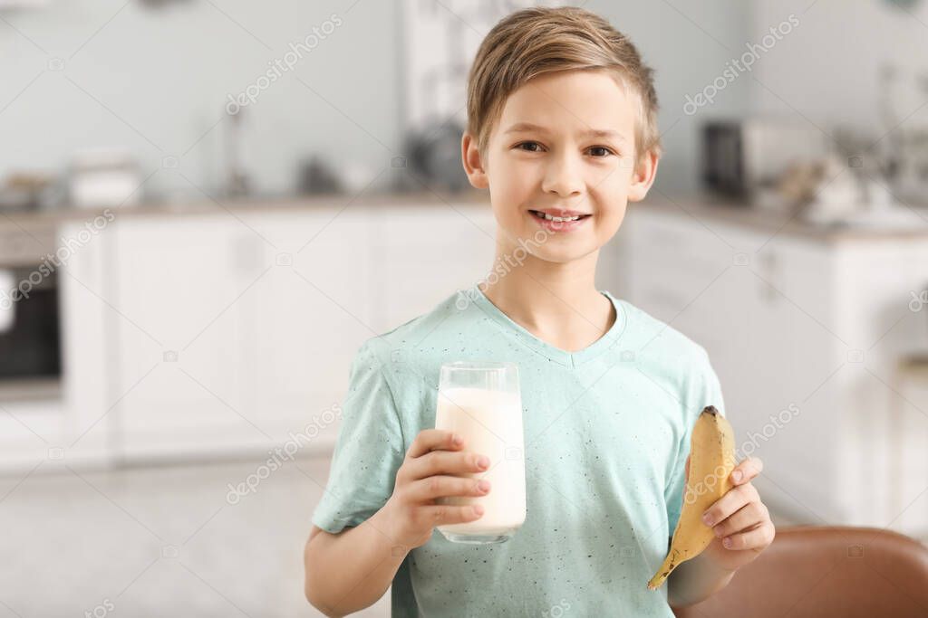 Little boy with milk and banana in kitchen