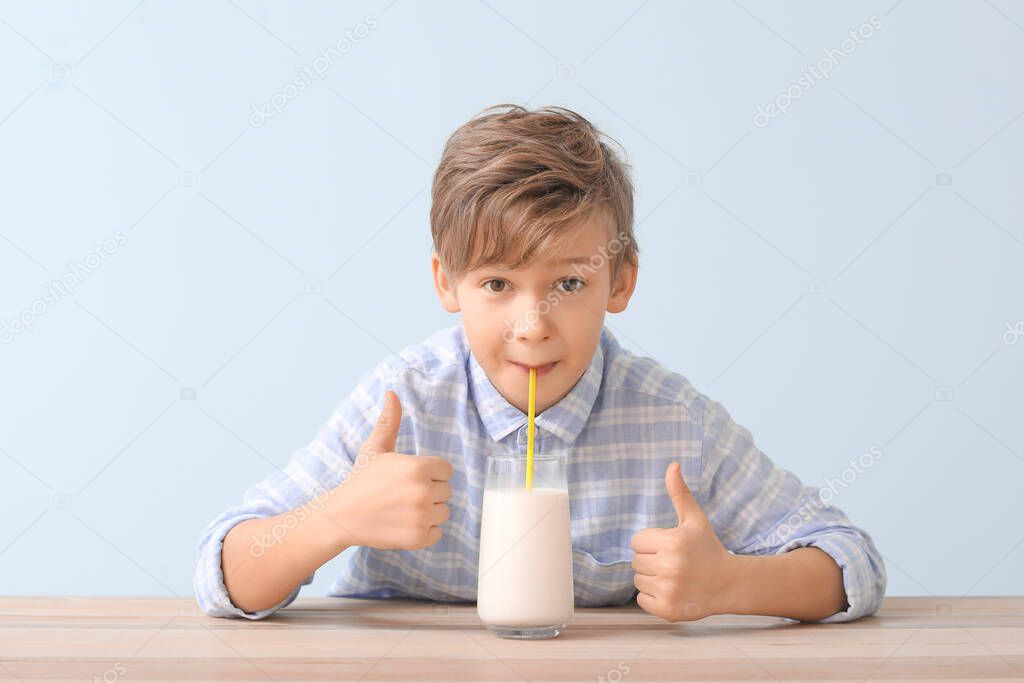 Little boy with milk showing thumb-up on color background