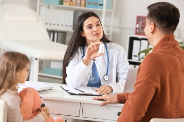 Küçük kızıyla birlikte çocuk doktorunu klinikte ziyaret eden bir adam.