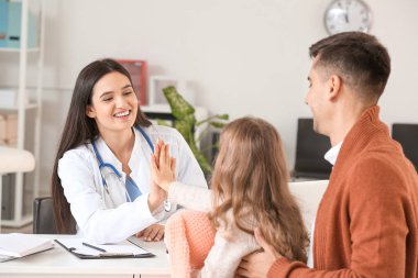 Küçük kızıyla birlikte çocuk doktorunu klinikte ziyaret eden bir adam.