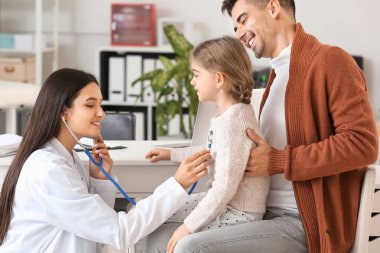 Küçük kızıyla birlikte çocuk doktorunu klinikte ziyaret eden bir adam.