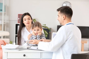 Küçük kızı olan bir kadın çocuk doktorunu klinikte ziyaret ediyor.